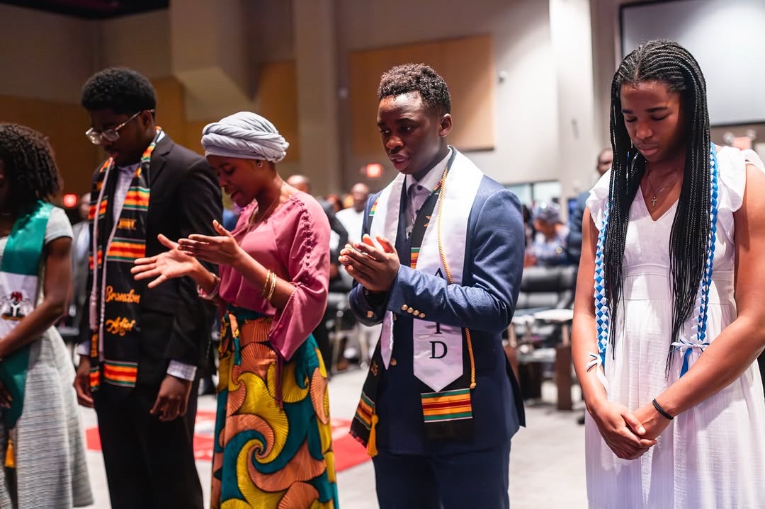 Young adults standing together in prayer during a service